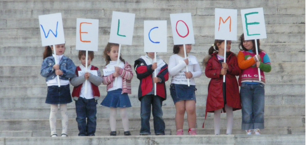children holding up signs that spell the word WELCOME